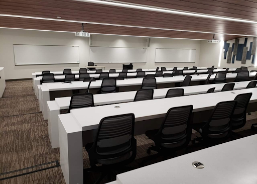 阿尔伯图斯·马格努斯科学大楼的演讲厅，白色的长桌和电脑转椅排成一行, 最高一层在后面, 所有人都面对着房间低前面的白板.