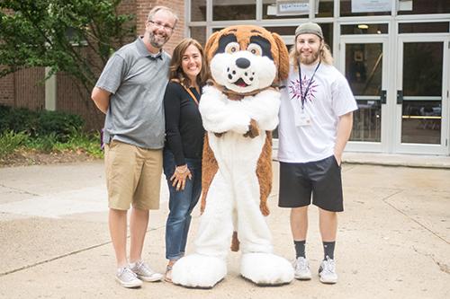 student, parents, and mascot standing outside a dorm