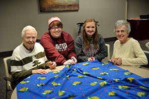 students and sisters making a blanket