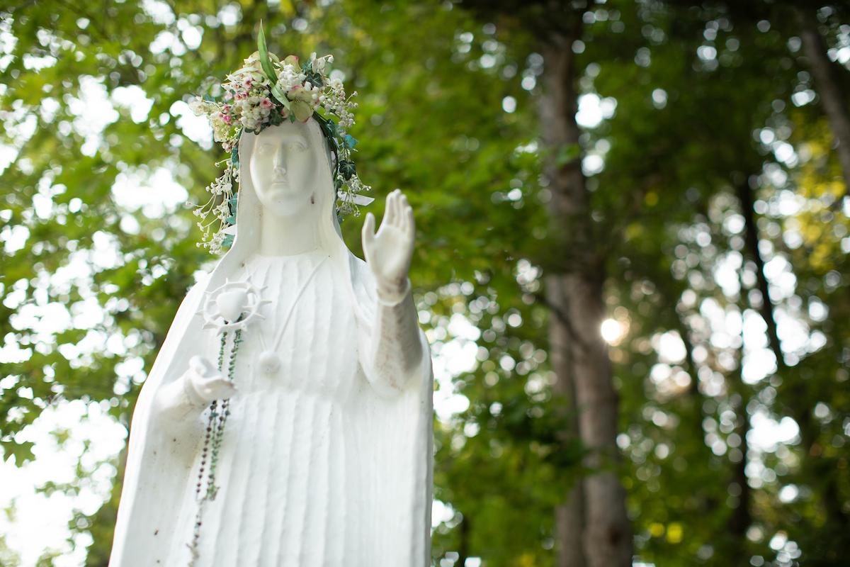 法蒂玛夫人的雕像，花冠和念珠，背景是树叶