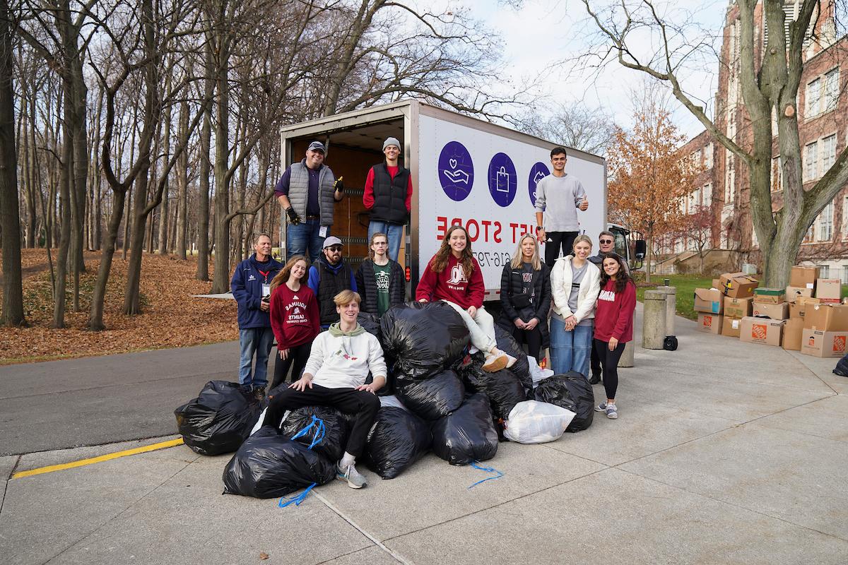 Several students stand with piles of garbage bags full of donations for Mel Trotter and a Mel Trotter Truck