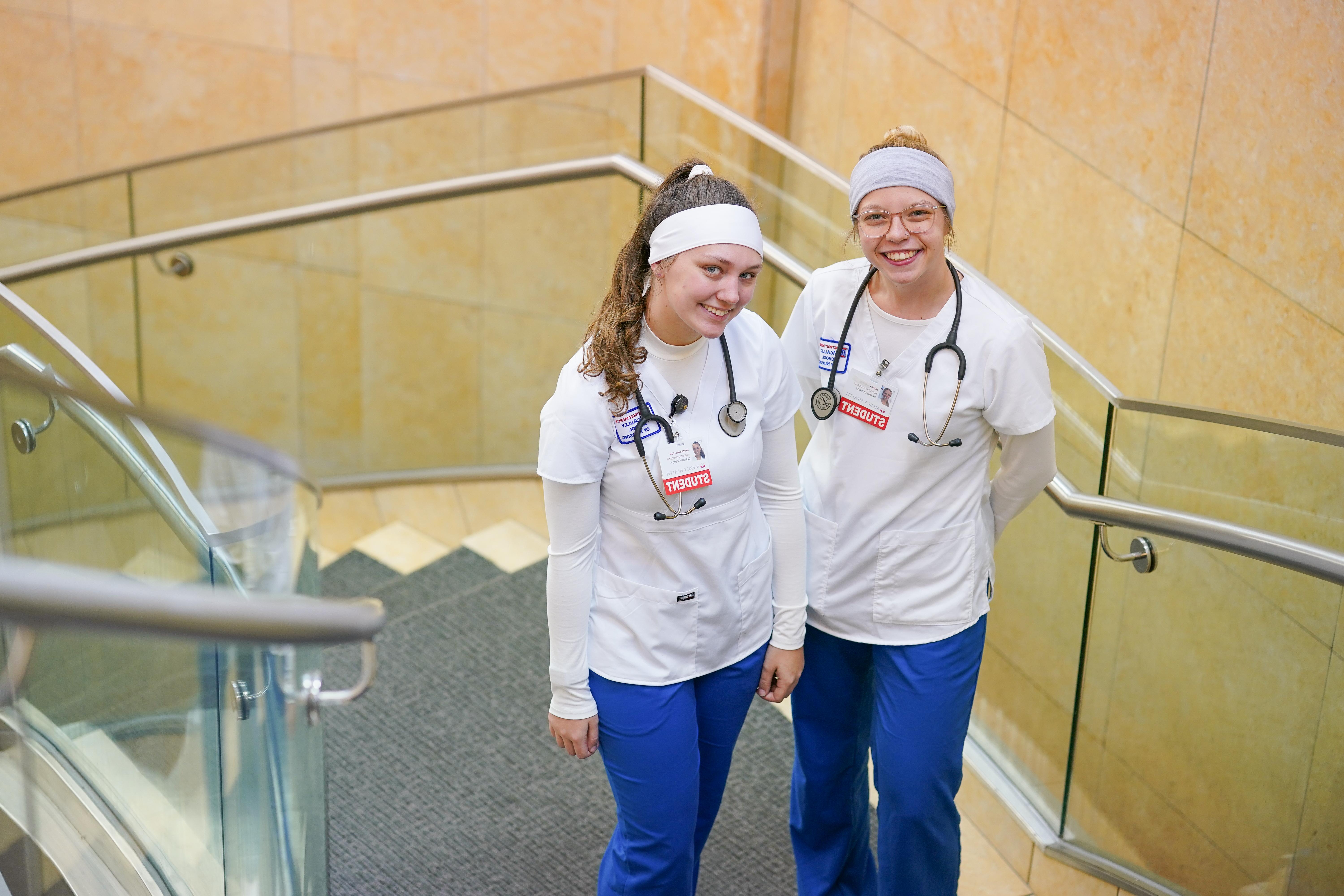 Two students in scrubs smiling
